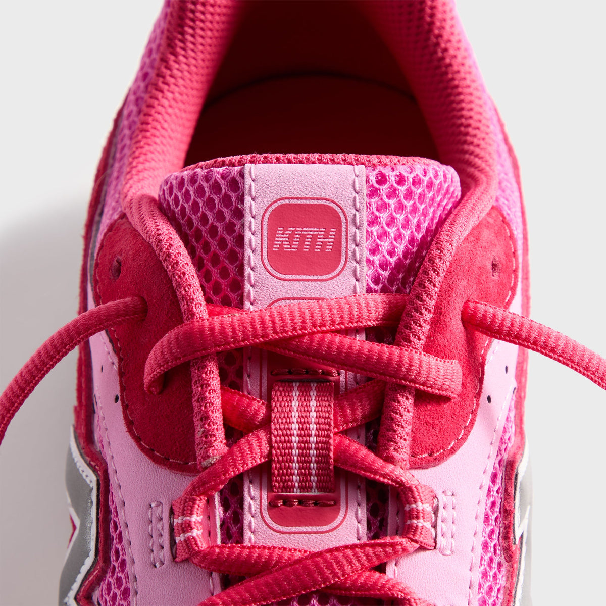 Kith & New Balance 204L in Camellia, top-down close-up of the mesh tongue with KITH tab and red laces