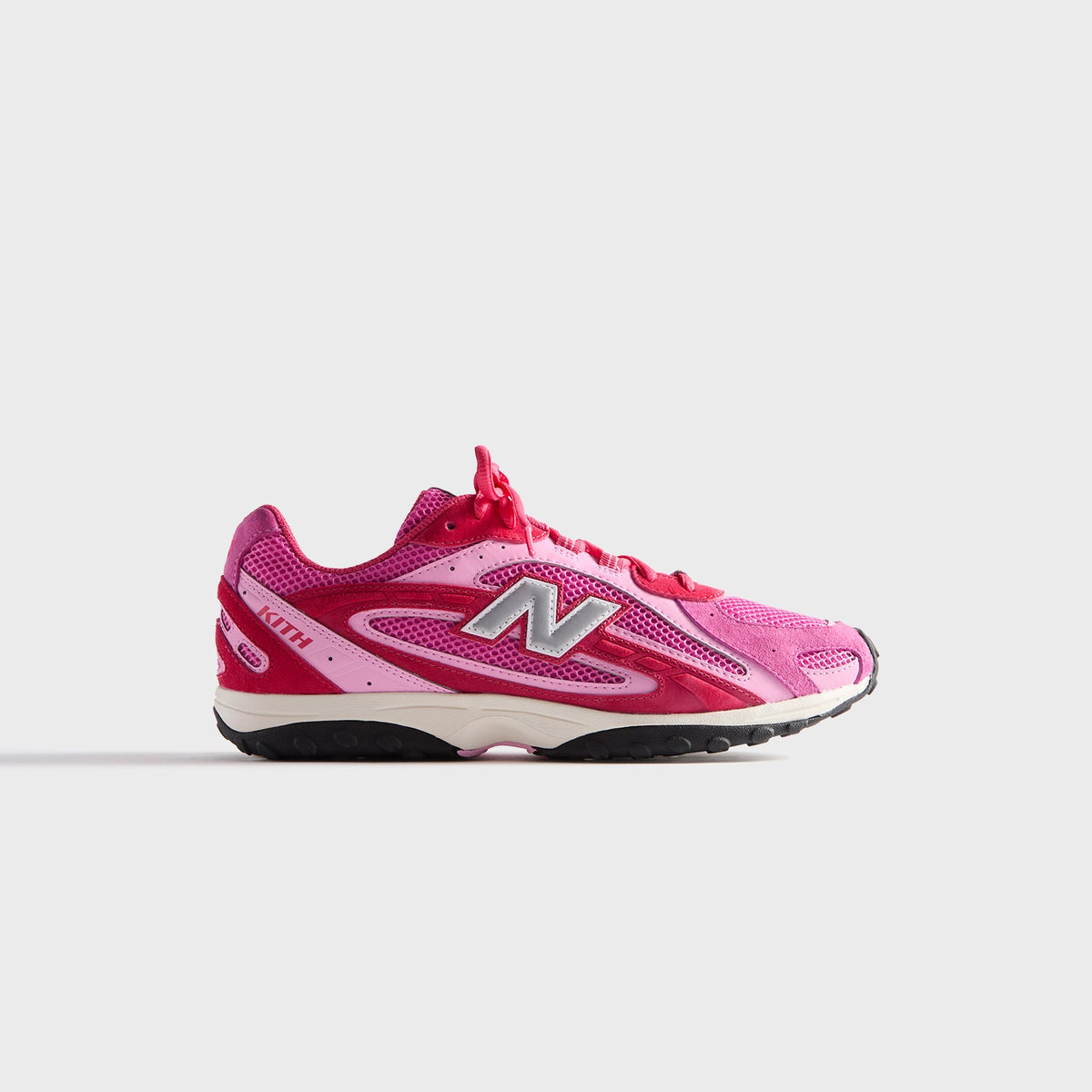 Kith & New Balance 204L in Camellia, lateral profile of the right sneaker in pink and red suede with mesh and silver N logo