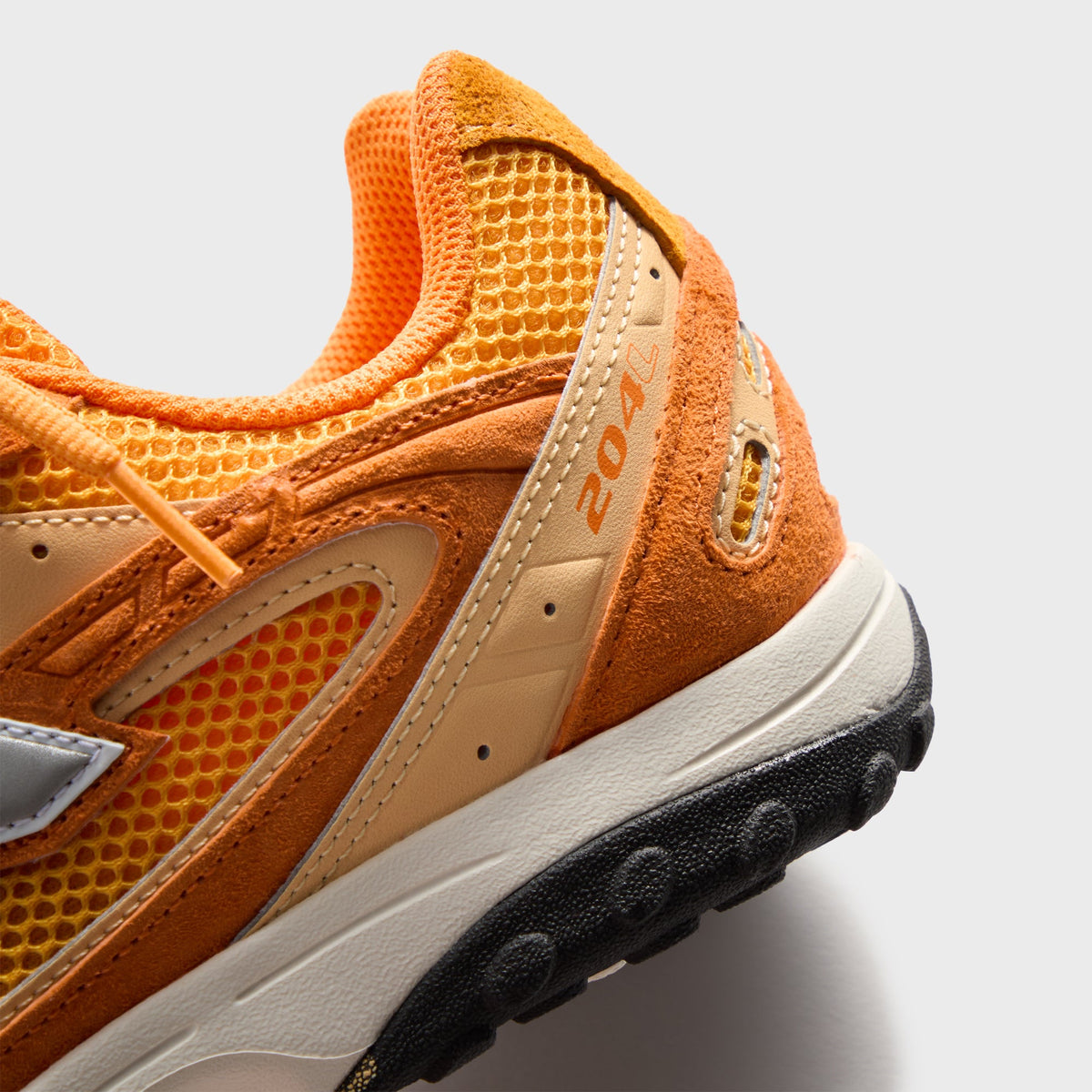 Kith & New Balance 204L in Sunburst, close-up of the orange suede heel and midfoot with 204 branding and mesh
