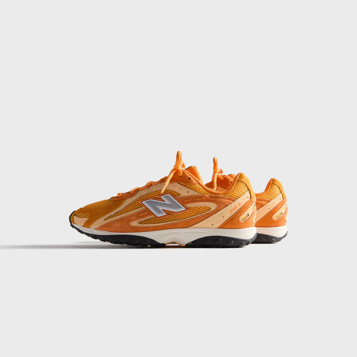 Kith & New Balance 204L in Sunburst, medial side profile of the single sneaker with inner N logo and orange mesh