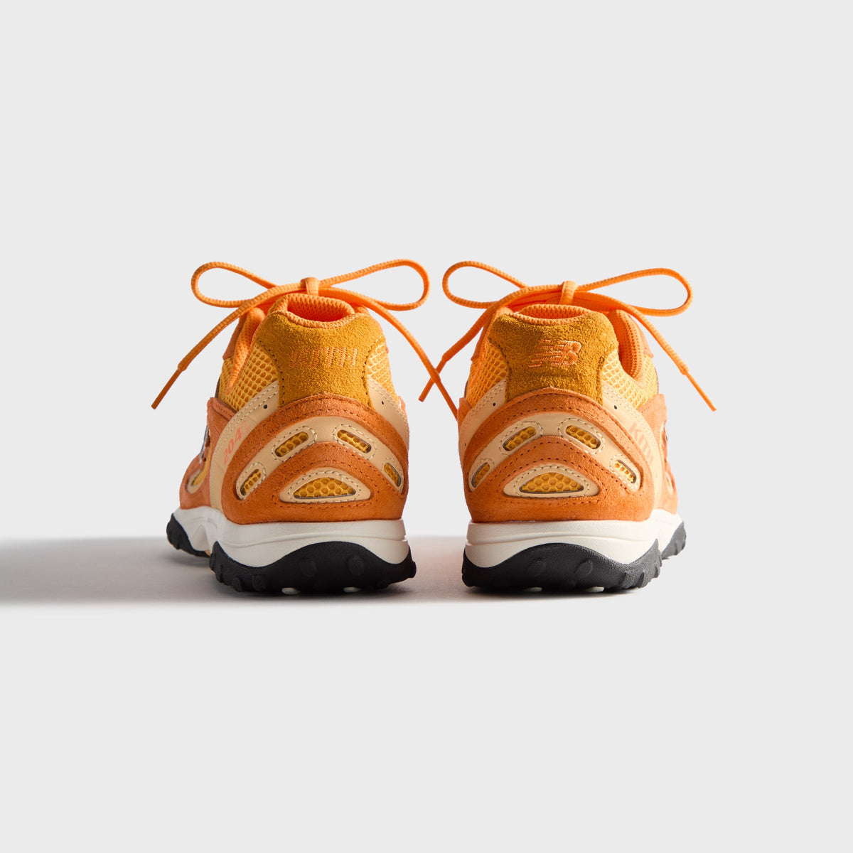 Kith & New Balance 204L in Sunburst, rear view of the orange pair showing heel counters and lace bows