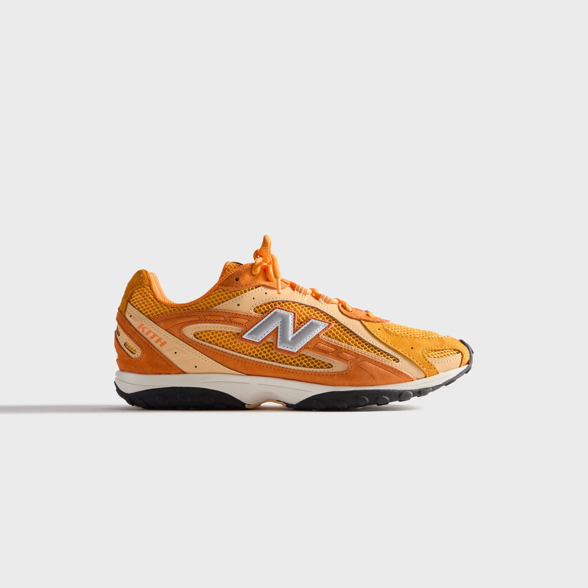 Kith & New Balance 204L in Sunburst, lateral profile of the right sneaker in orange and tan suede with mesh and silver N logo