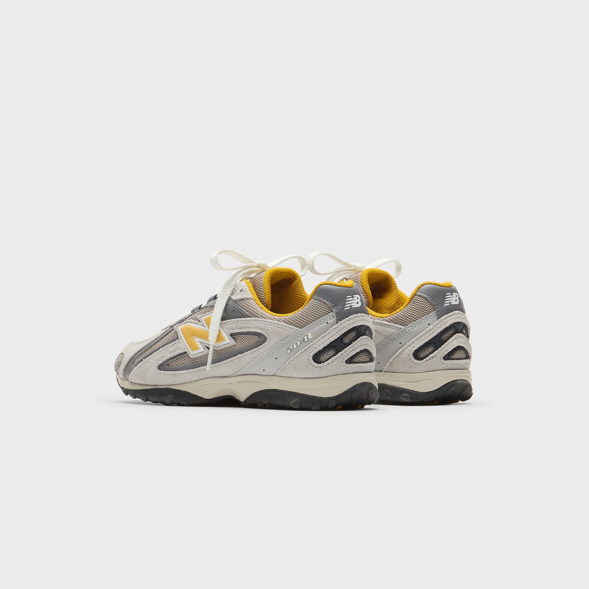 Kith x New Balance 204L sneakers in grey and yellow, rear heel view showing the silver N logo