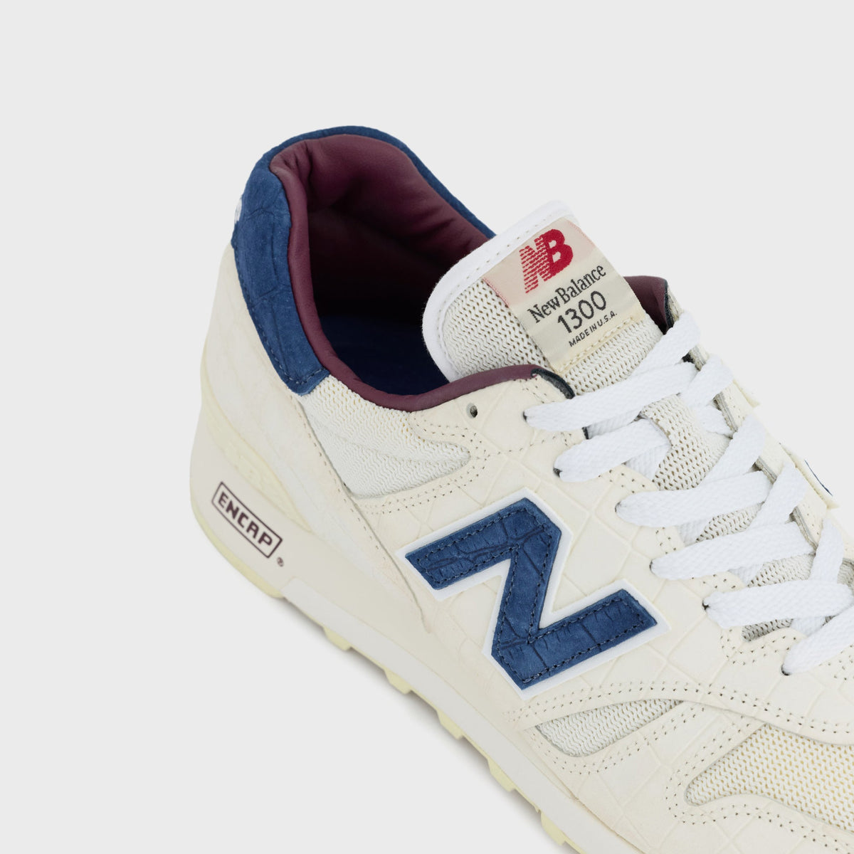 New Balance Made in USA 1300 sneaker in Angora, close-up of the Blue Oyster suede heel tab and 1300 Made in USA tongue tag