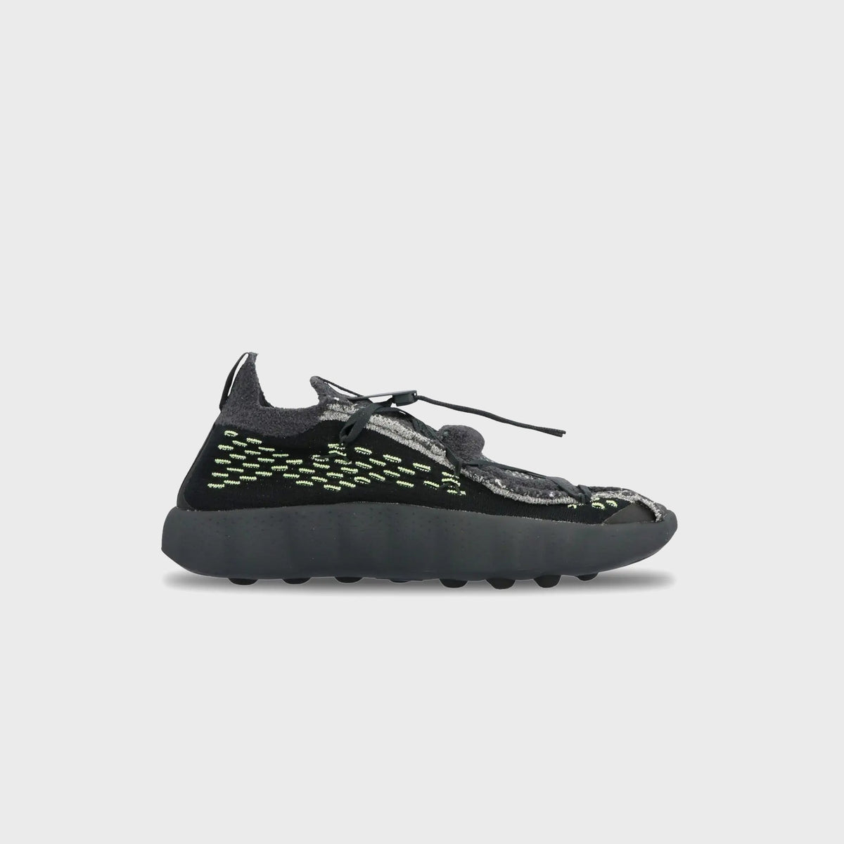 Nike Mind 002 Flyknit in black and anthracite with volt green stitching and dark grey nodular sole, side profile