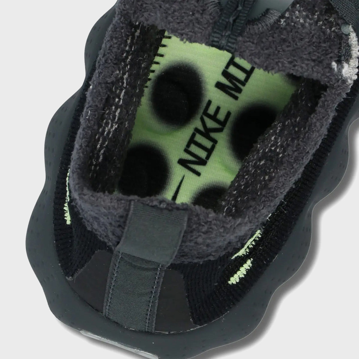 Close-up of Nike Mind 002 Flyknit collar showing volt green insole with Nike Mind print and black nodes