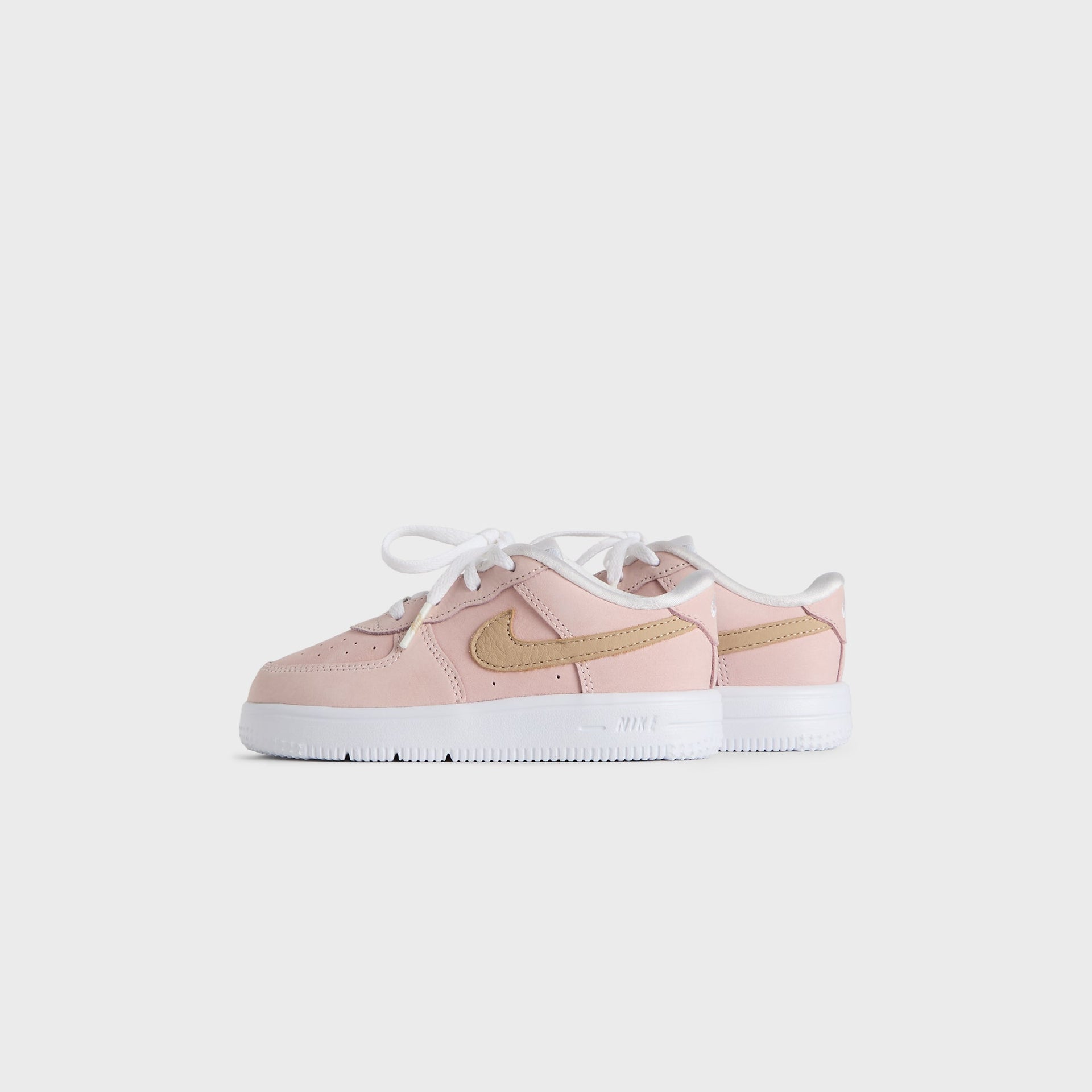 Kith Kids x Nike TD Air Force 1 Un-Linen pair, small front three-quarter angle, pink upper and wheat suede Swoosh