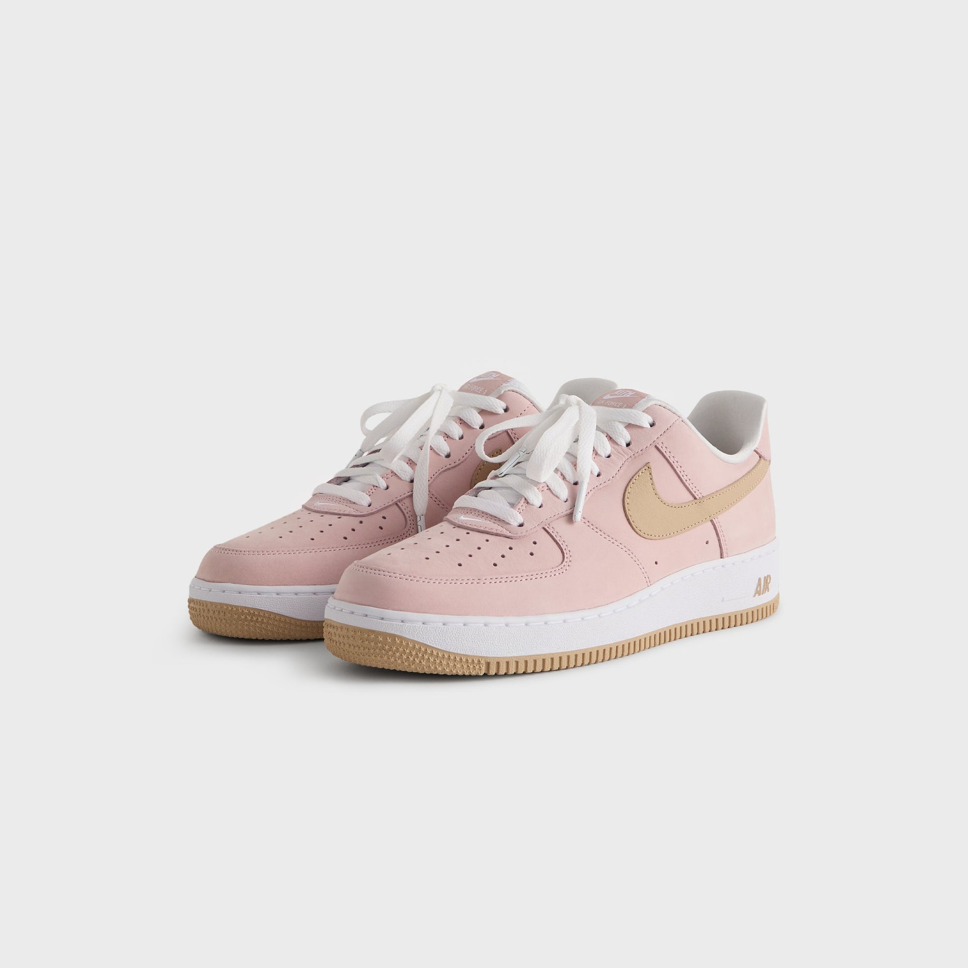 Kith for Nike Air Force 1 'Un-Linen' pink suede pair at front three-quarter angle with tan swooshes and gum soles