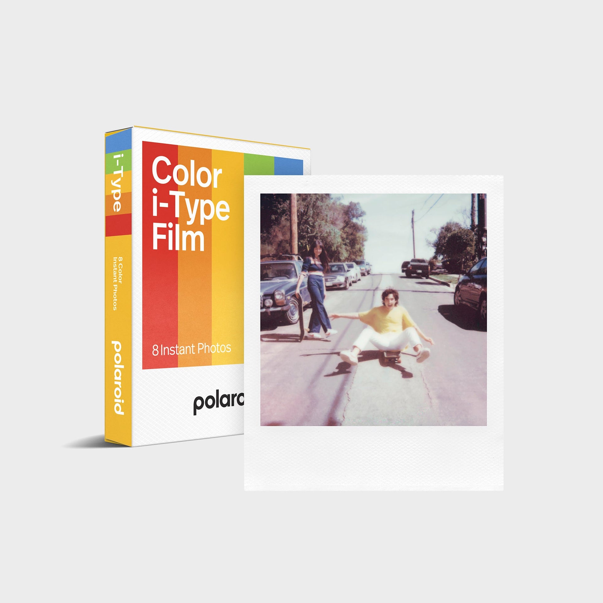 Polaroid Color i-Type Film box beside a developed instant photo of a skateboarder coasting down a sunny street