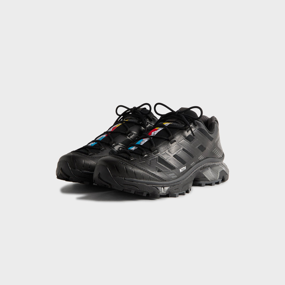Kith for Salomon XT-4K in Black, front three-quarter view of the pair showing multicolor lace-panel accents and quicklaces