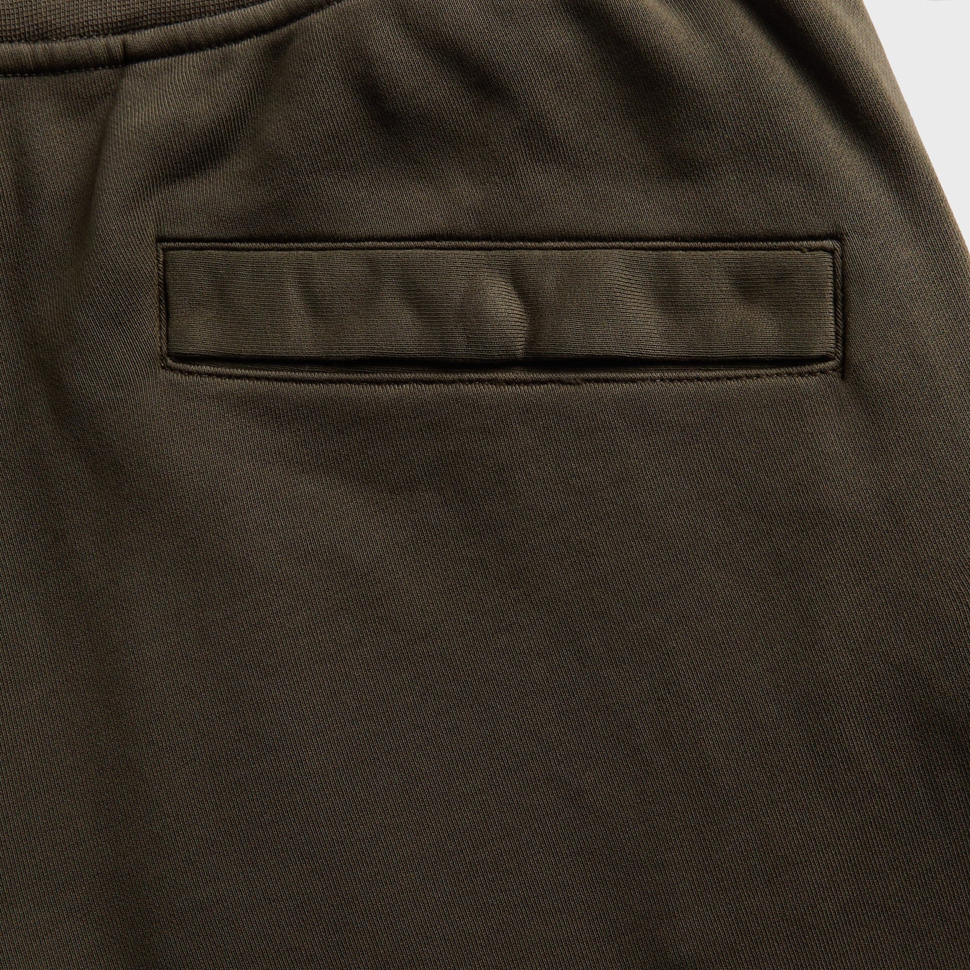 Close-up of dark olive fleece sweatpants back welt pocket with tonal stitching