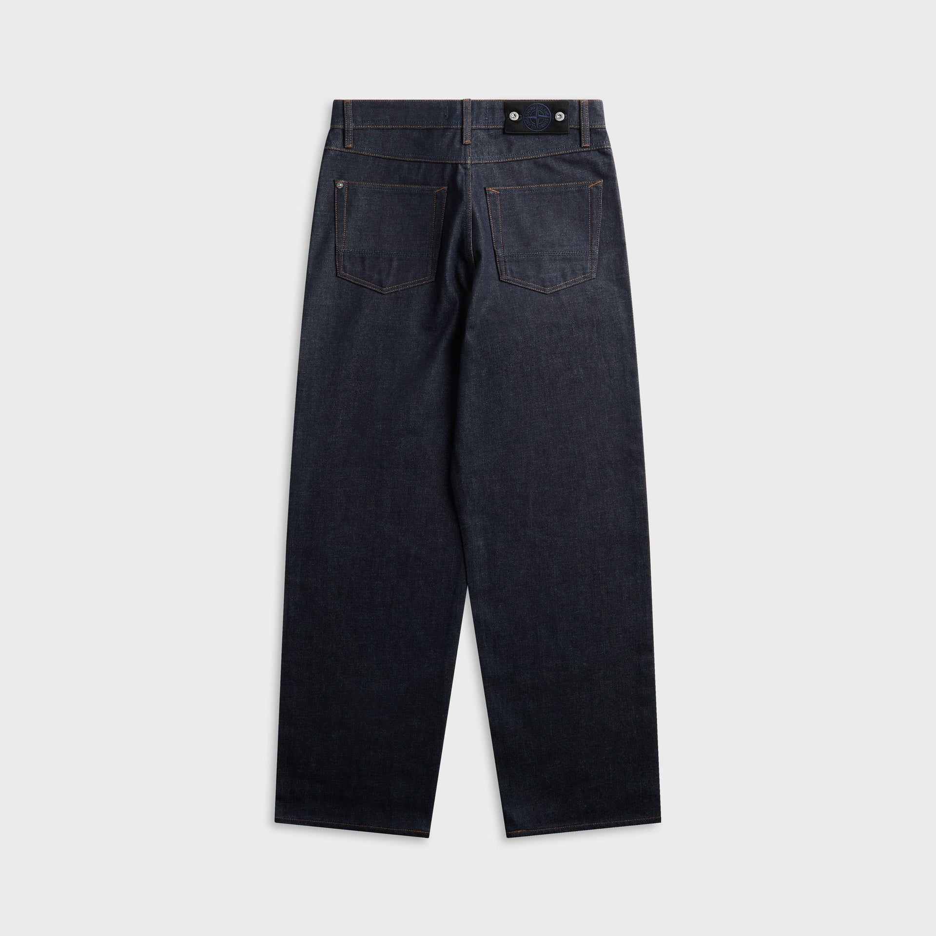 Raw indigo Stone Island loose-fit jean, back view with patch pockets and leather waistband tab