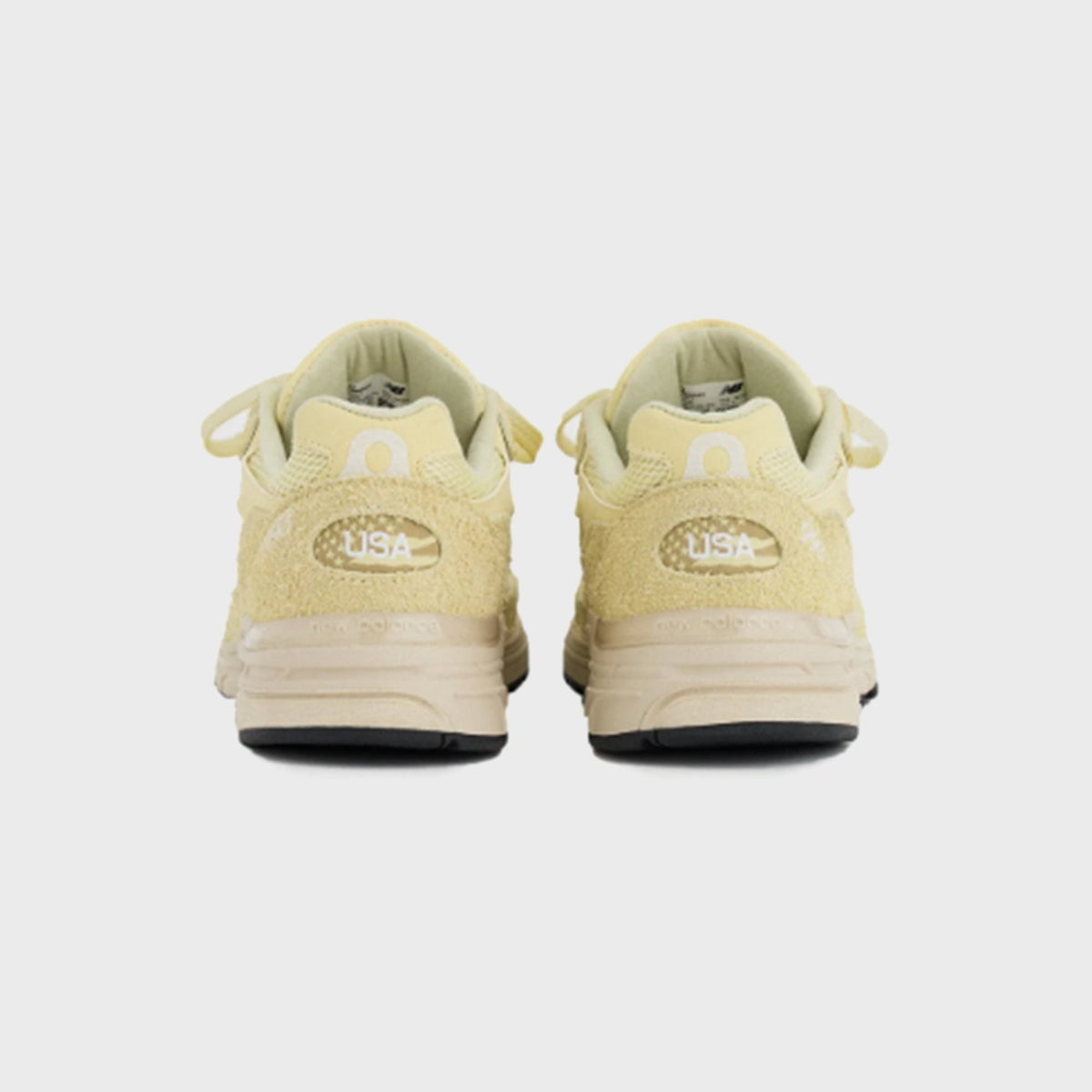 New Balance 993 Made in USA sneaker in pale yellow suede, rear heel view of pair showing USA flag patch