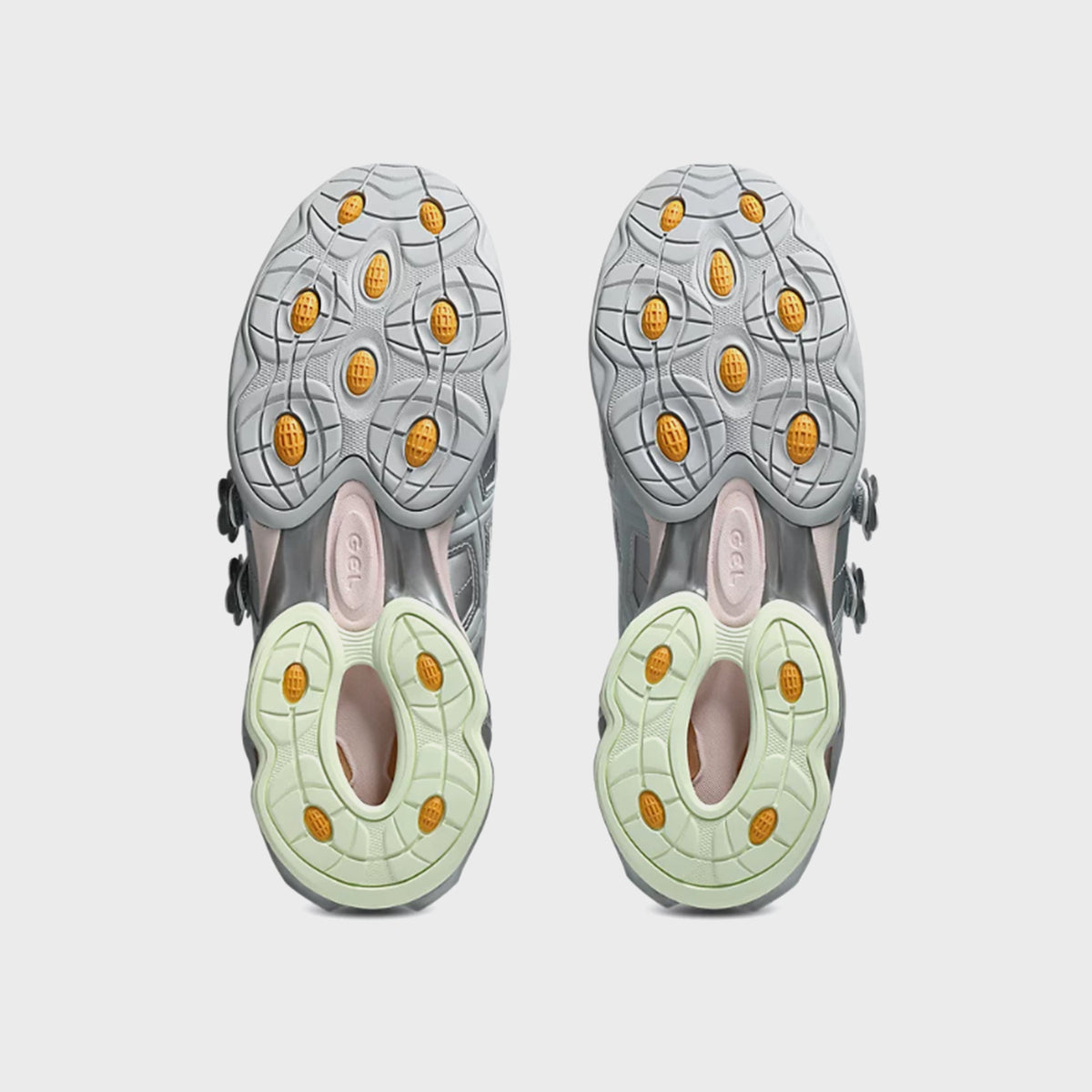 Outsole view of ASICS x Cecilie Bahnsen GEL-KINETIC FR pair showing amber GEL cushioning pods and glow-green rubber lugs
