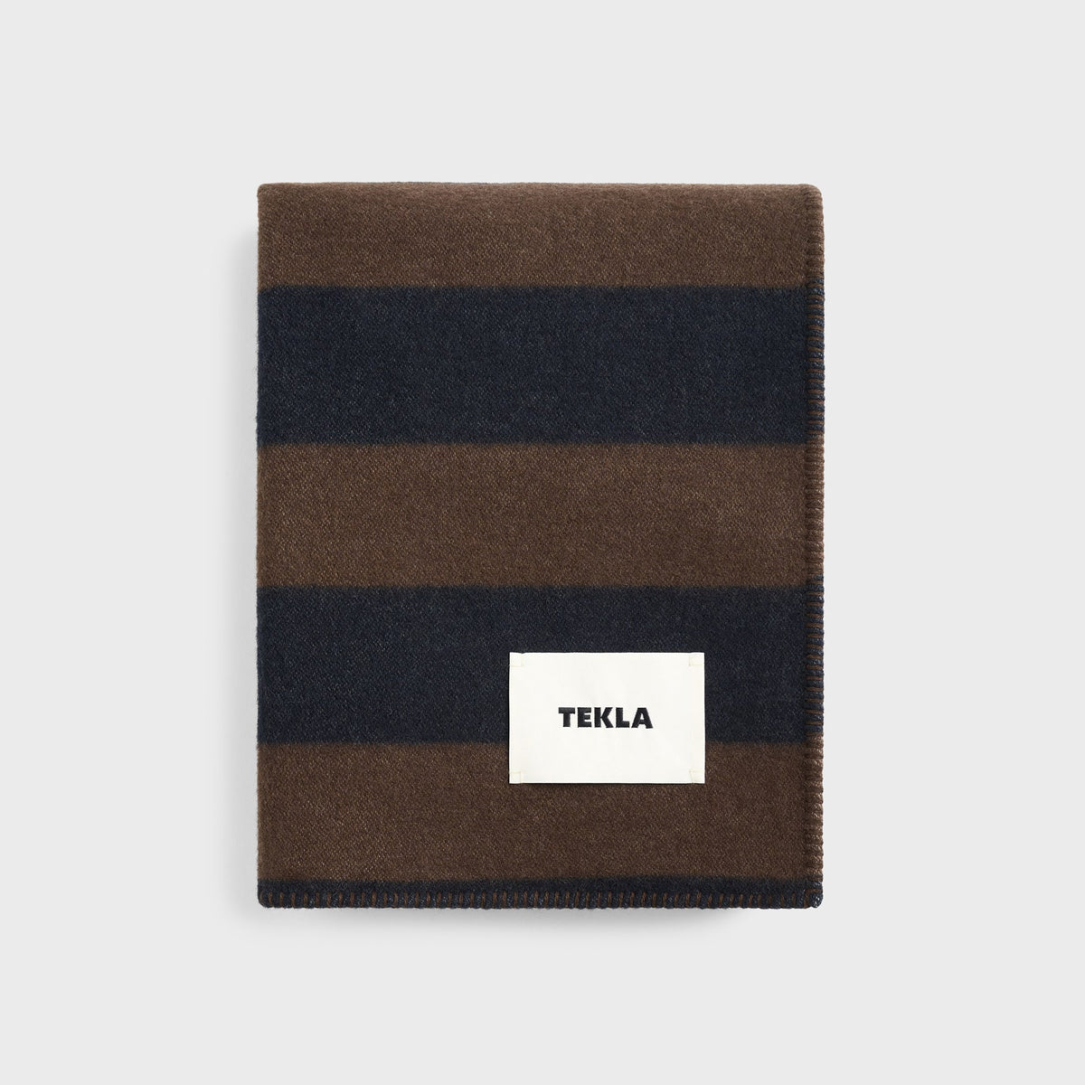 Tekla Lambswool Blanket in Walnut / Dusk Blue Stripes, folded brown and navy striped wool blanket with TEKLA label