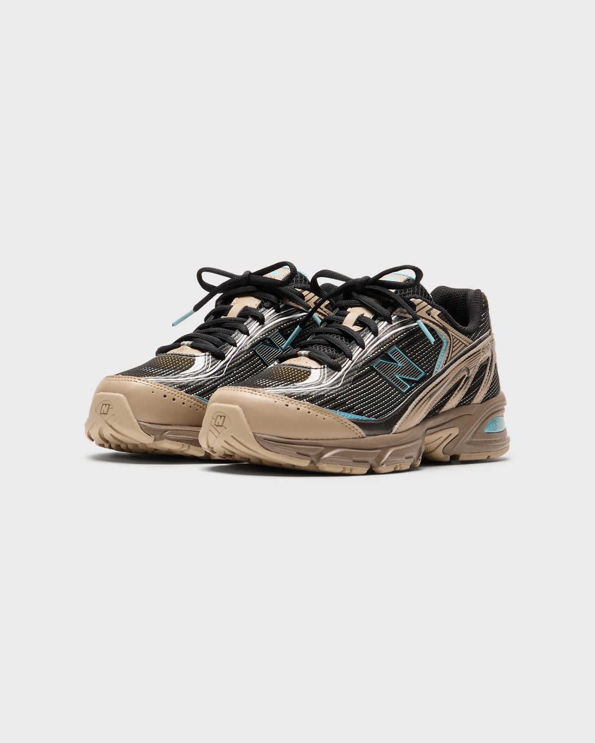 New Balance sneakers in tan, brown and black with teal accents and black laces, pair in three-quarter view