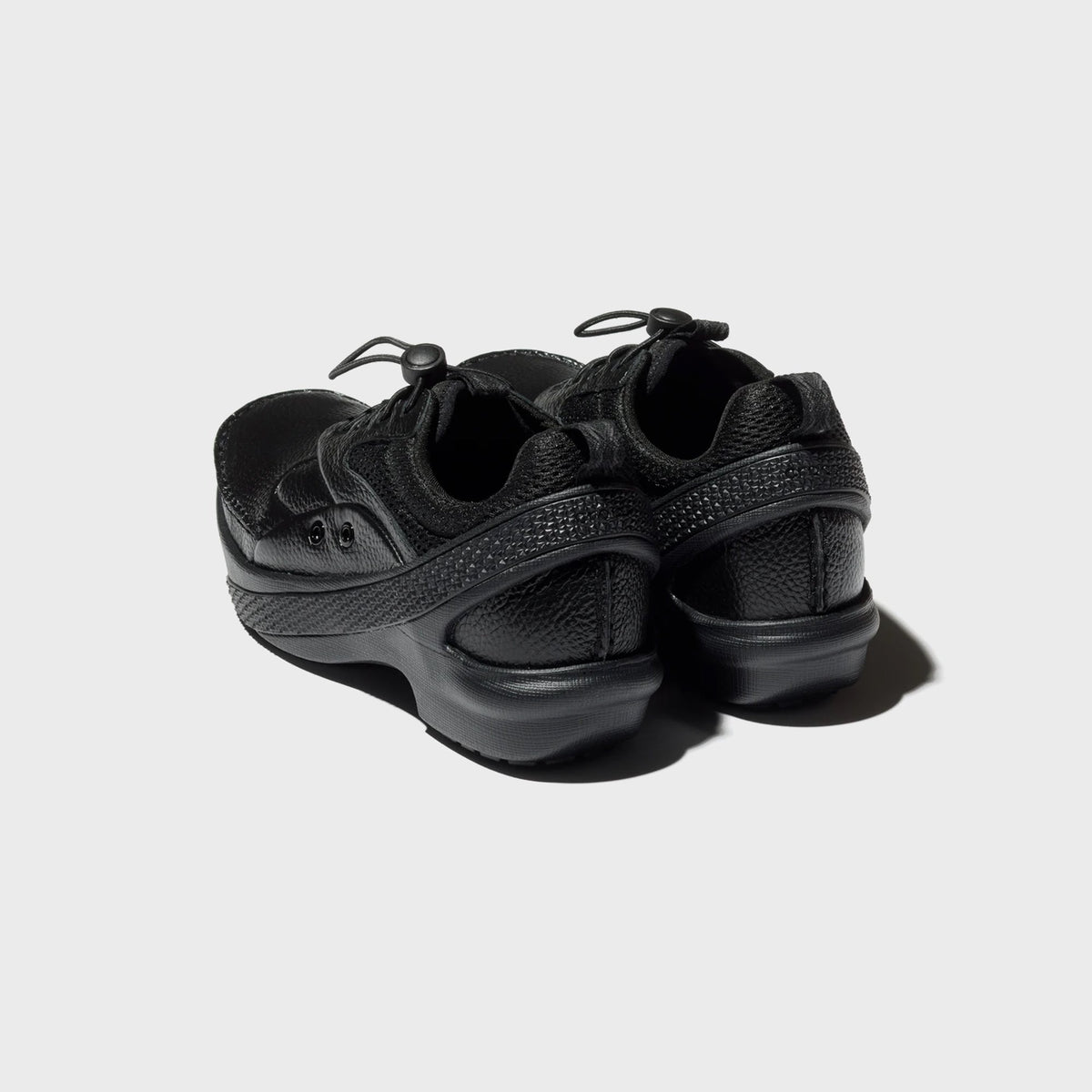 Crocs x Kiko Kostadinov VAALS in black, pair shown from rear three-quarter angle with textured sculpted heel band and mesh collar